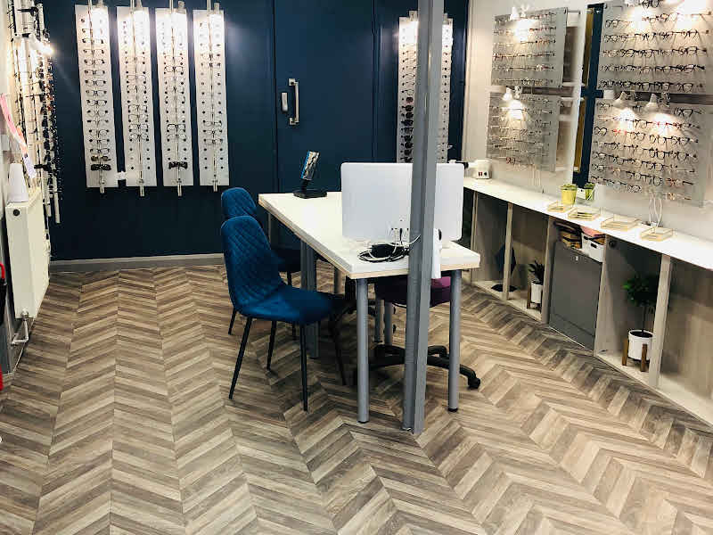 Modern optical store interior with eyeglass displays and customer consultation station
