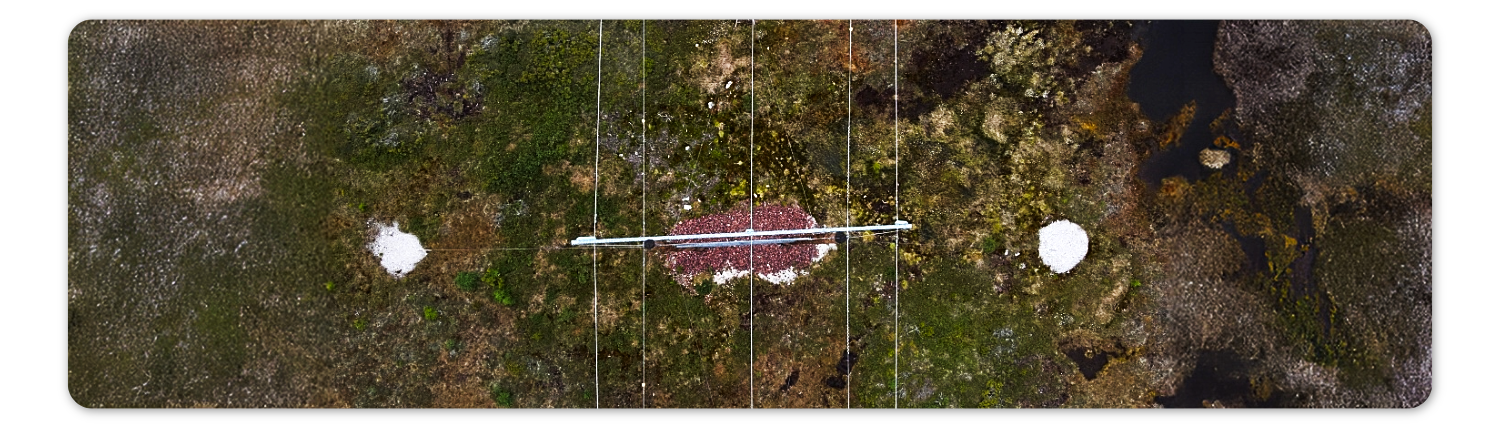 Overhead drone view of transmission tower in remote terrain for HVDC line inspection.