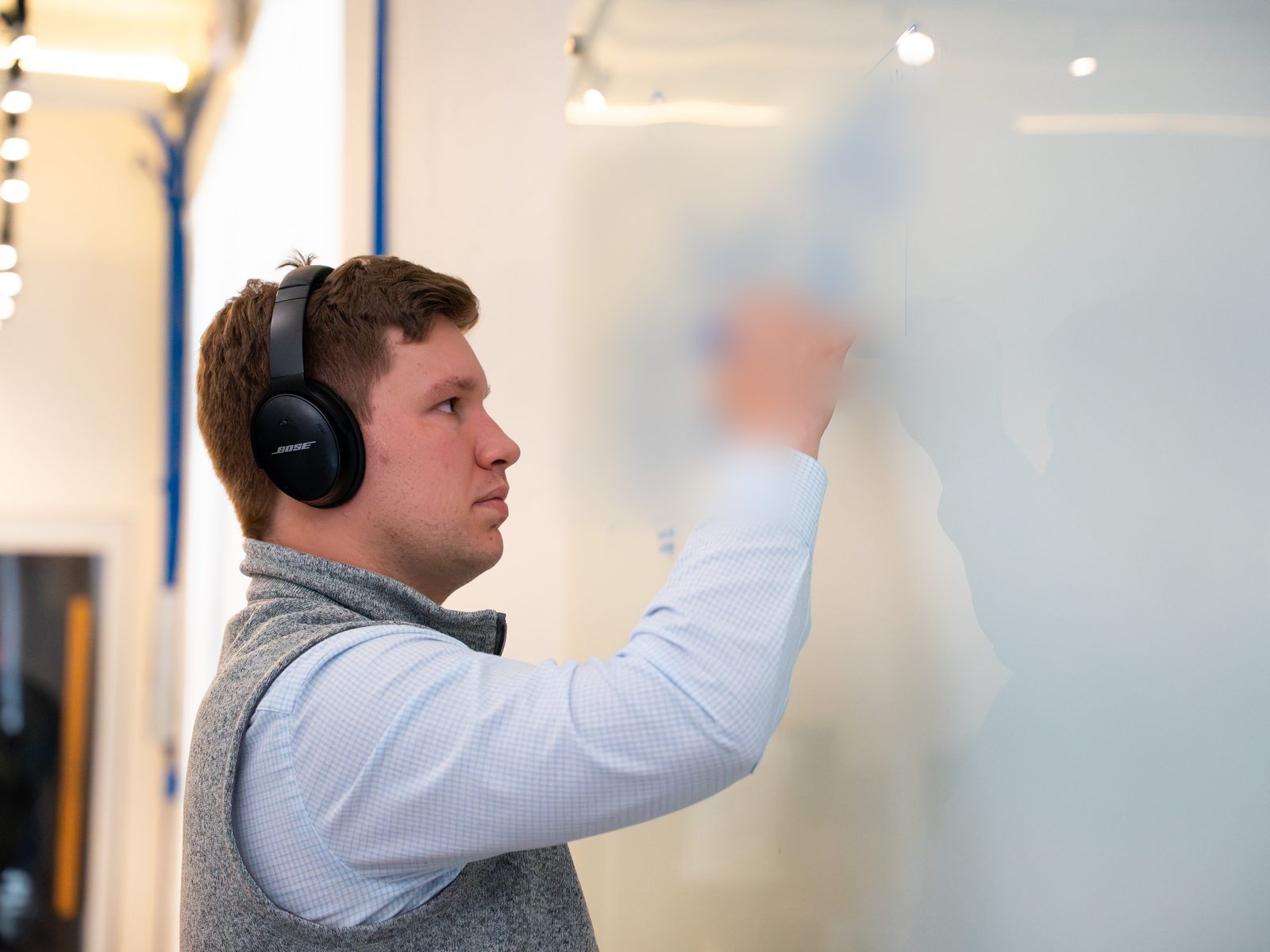 A hackathon participant maps a process on a whiteboard at Detect's office - board notes blurred for confidentiality