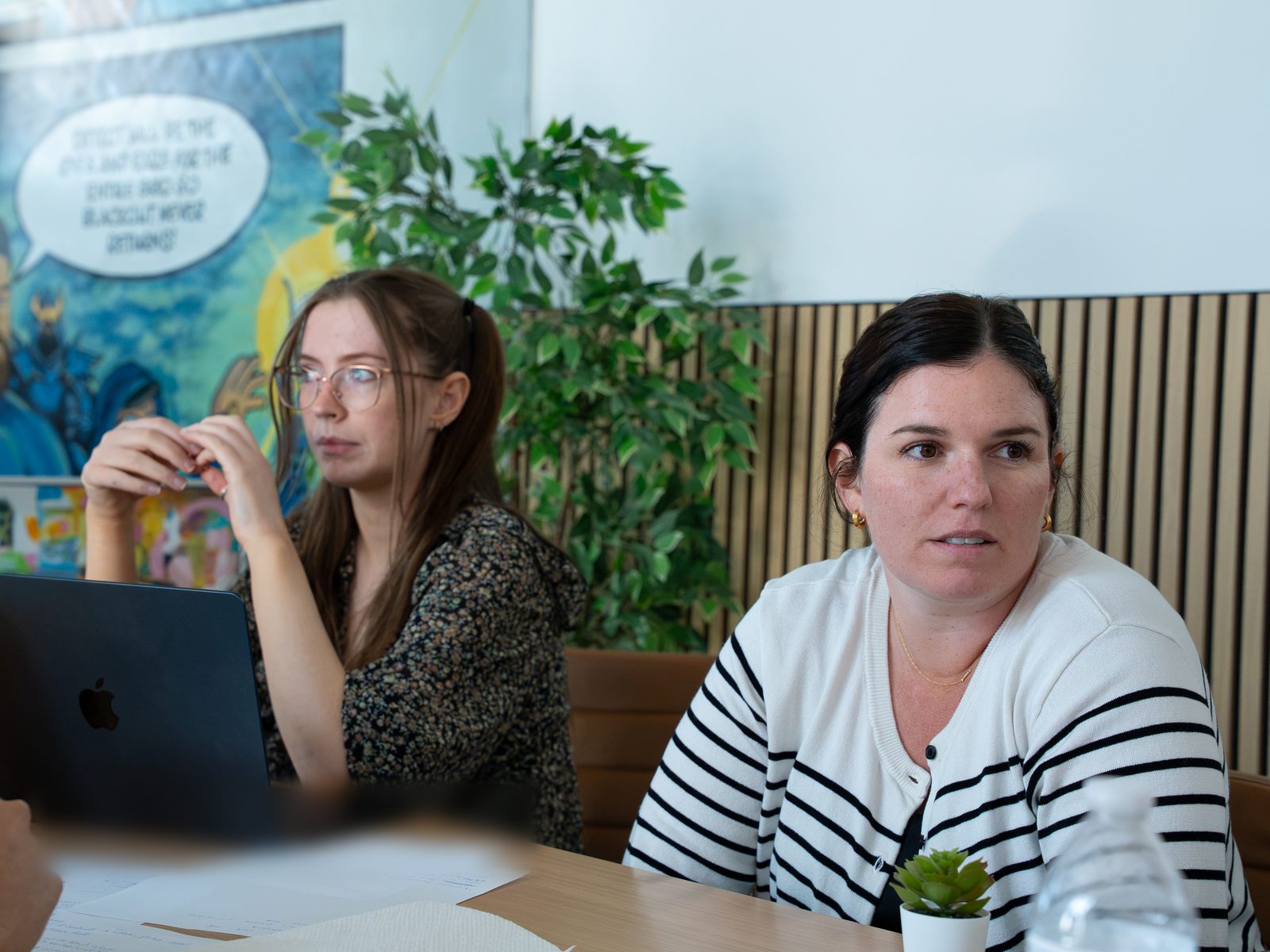 Hackathon teammates work through a problem statement in front of the story mural at Detect's office