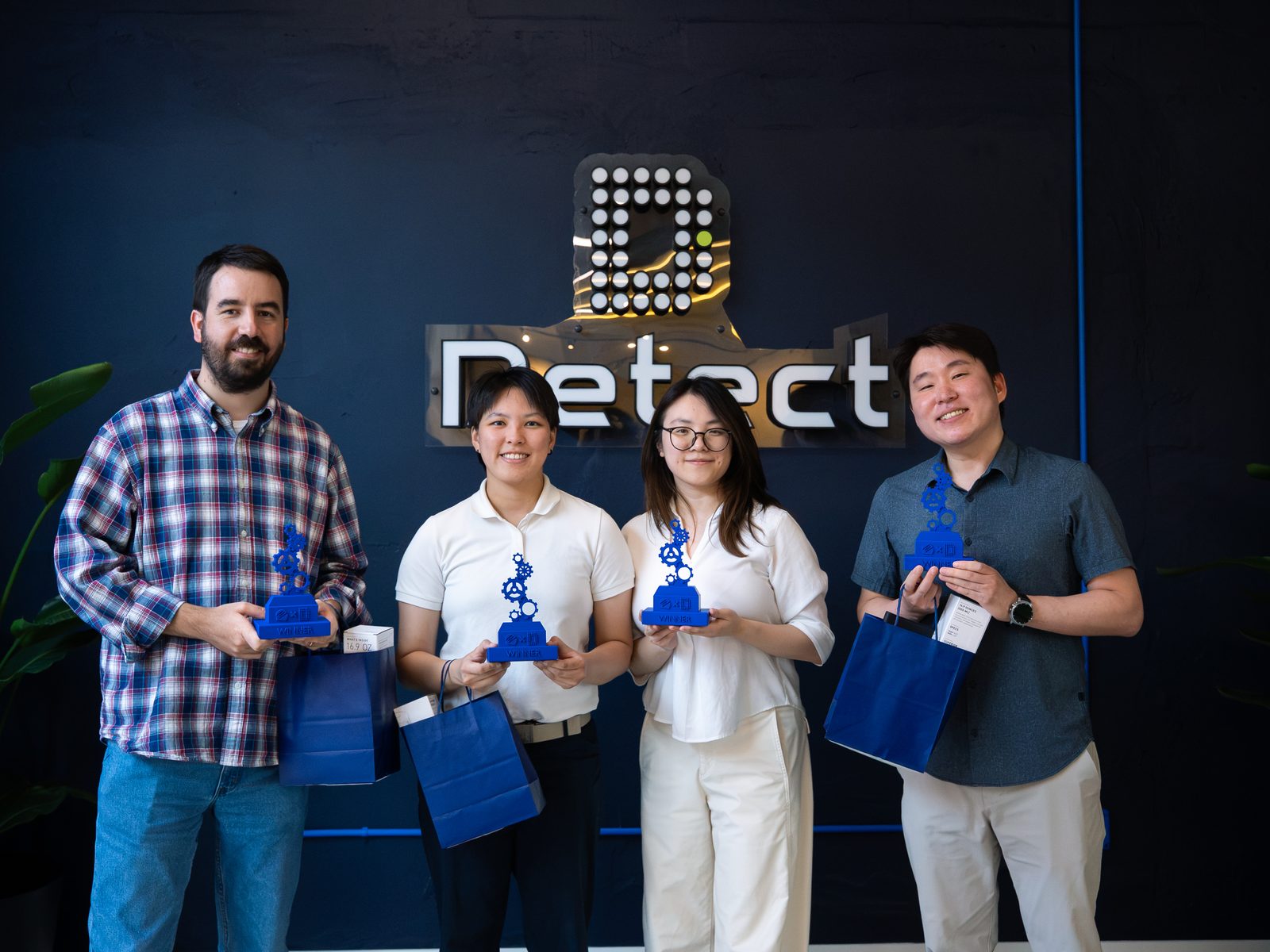 The winning team of the Detect × NextEra Energy Transmission AI hackathon holding 3D-printed trophies at Detect's office