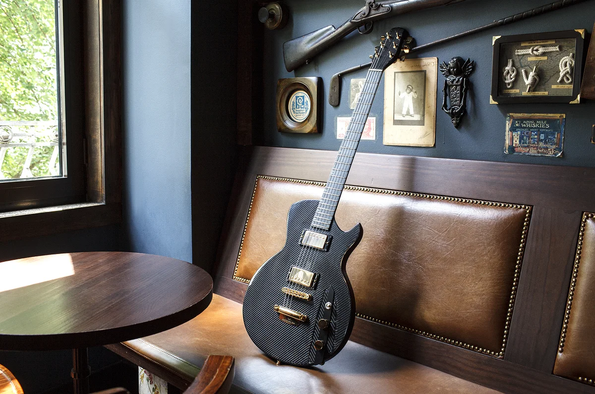 Fotografia de uma guitarra (carbono) pousada num banco.