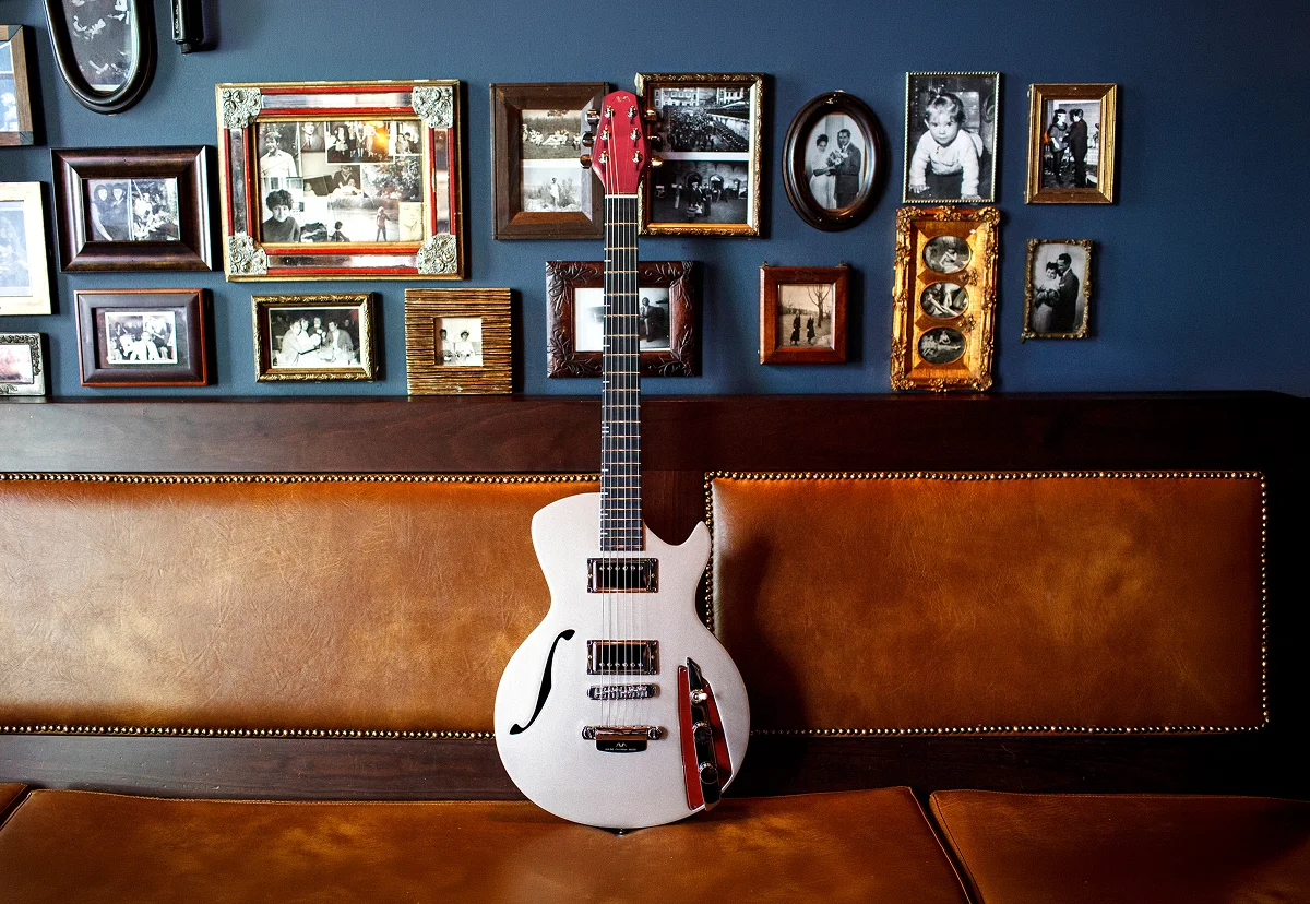 Fotografia de uma guitarra pousada num banco.