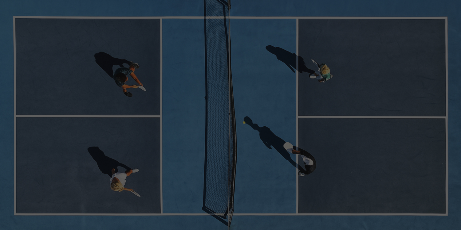 Aerial view of two people playing pickleball on a blue court with a net dividing them.