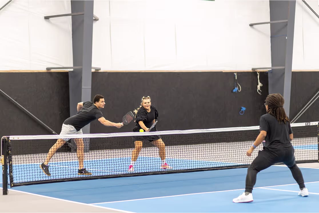Indoor golf simulator screen displaying golf course, shot metrics, and ball trajectory on artificial turf flooring.
