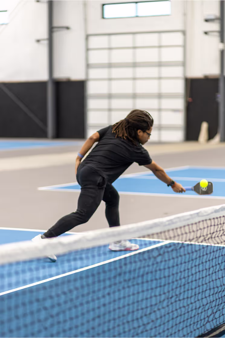 Indoor golf simulator screen displaying golf course, shot metrics, and ball trajectory on artificial turf flooring.