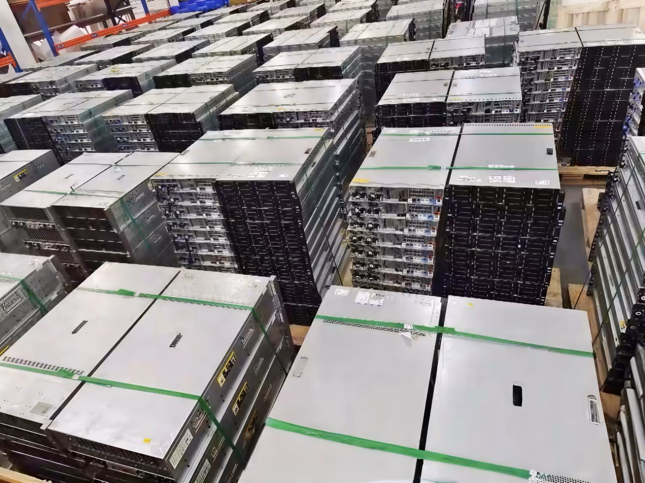 Warehouse filled with stacks of server hardware units packed and strapped on pallets.