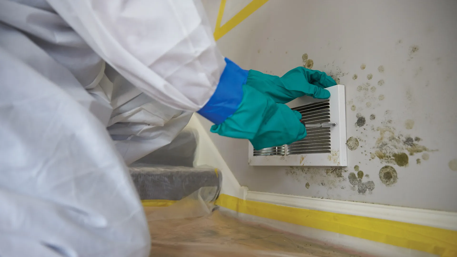 Technician in full PPE remediating mold in a residence