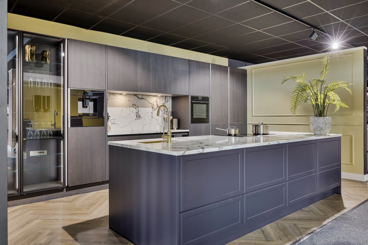 Moderne keuken met kookeiland, gouden kraan en glazen vitrinekast - Showroom Borculo Marboma