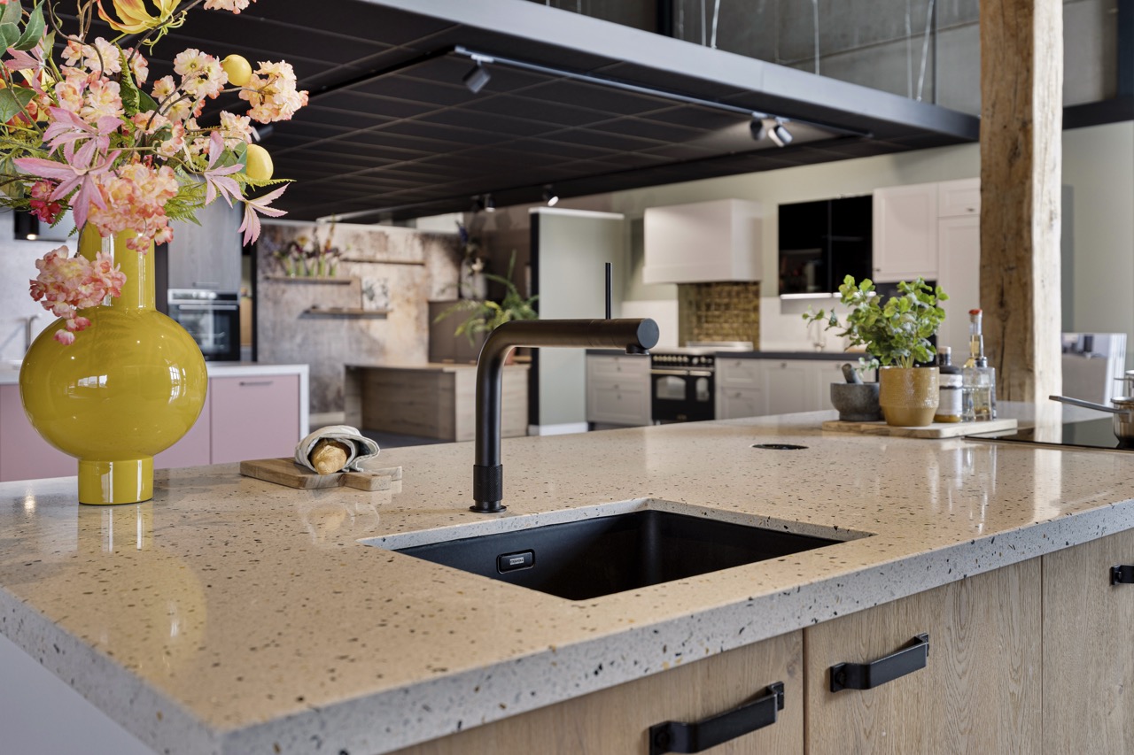 Zwarte spoelbak en kraan in terrazzo werkblad met houten fronten - Showroom Borculo Marboma