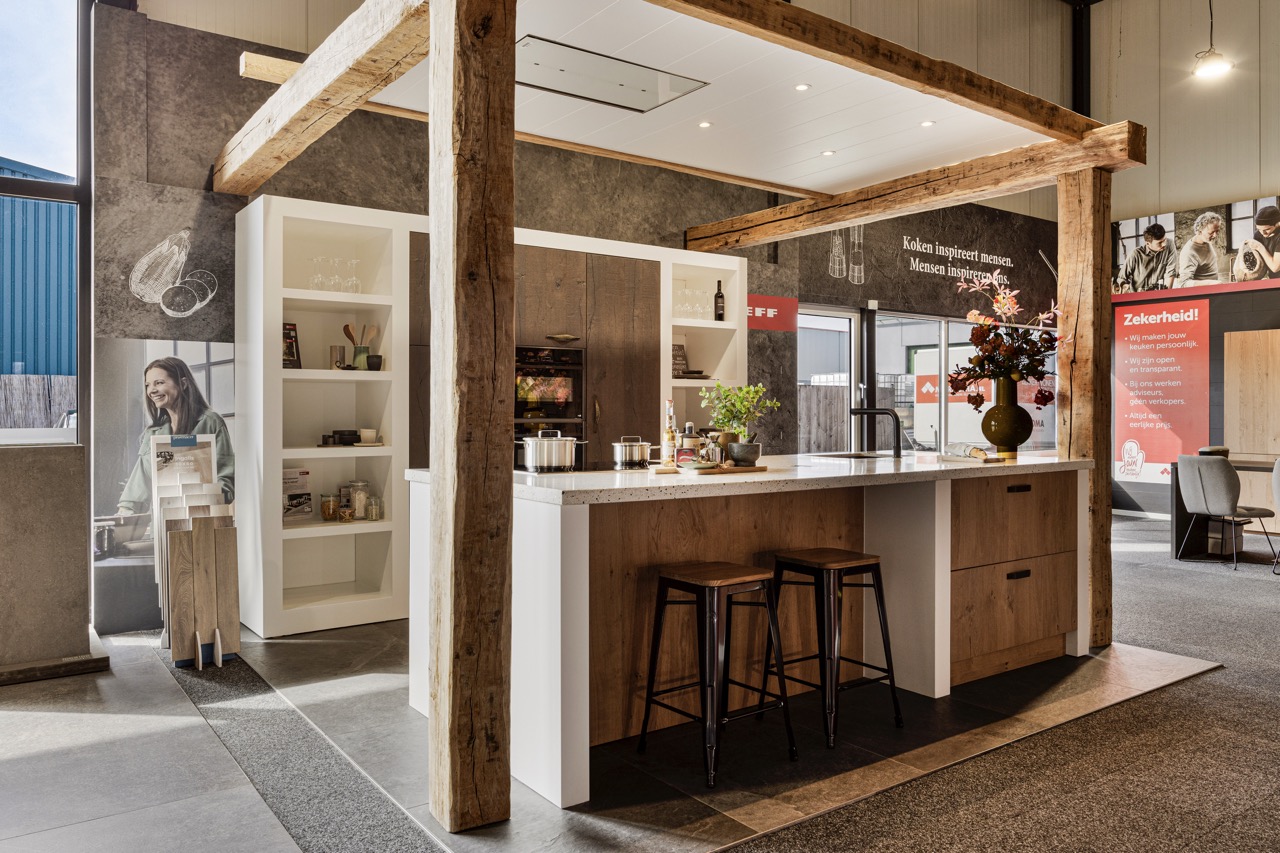 Landelijke keuken in houtlook met wit werkblad en barkrukken onder eiken balken - Showroom Borculo Marboma