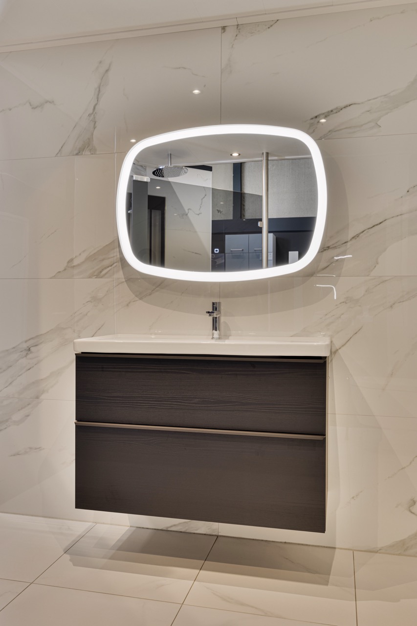 Donker badmeubel met verlichte spiegel en marmerlook tegels - Showroom Borculo Marboma