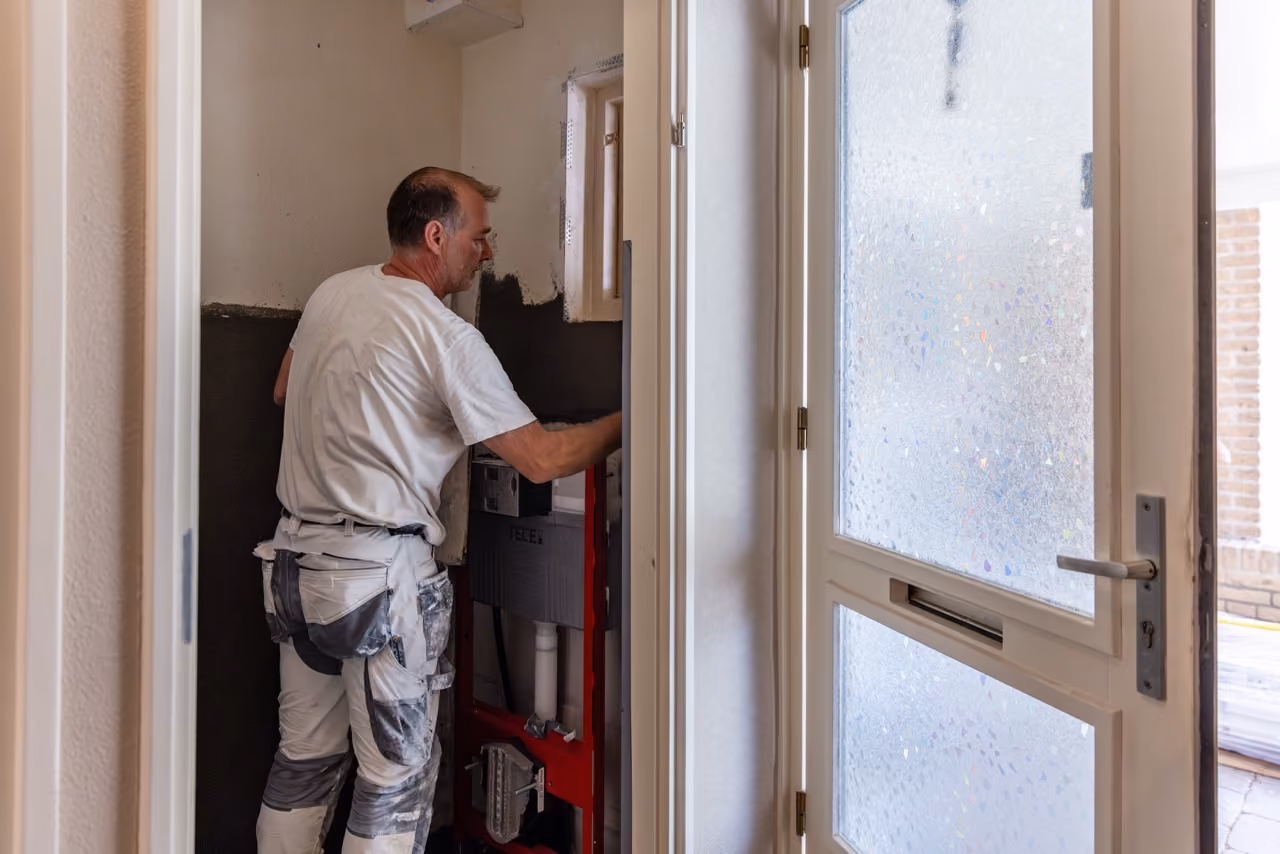 Vakman van Marboma plaatst een inbouwreservoir voor een hangend toilet