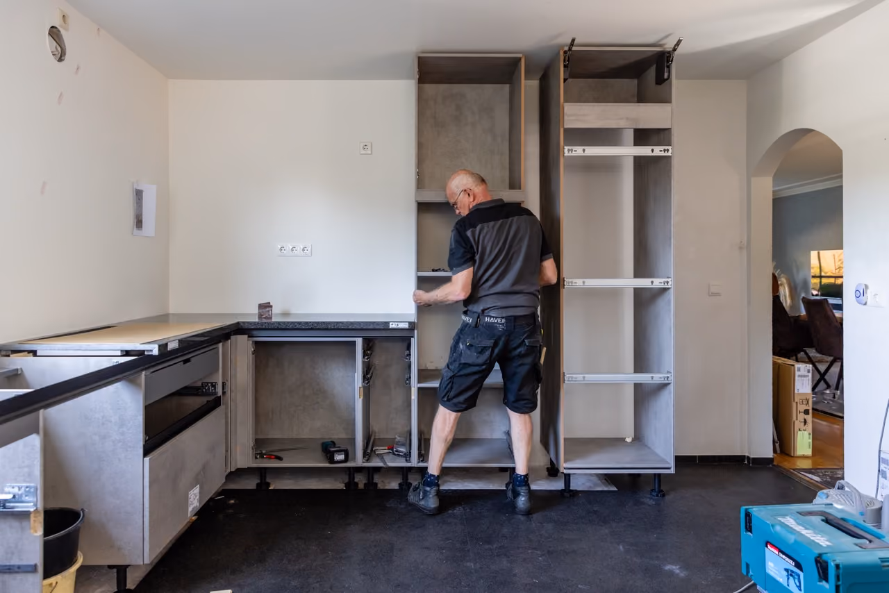 Monteur van Marboma plaatst de onderkasten en hoge kasten van een nieuwe keuken