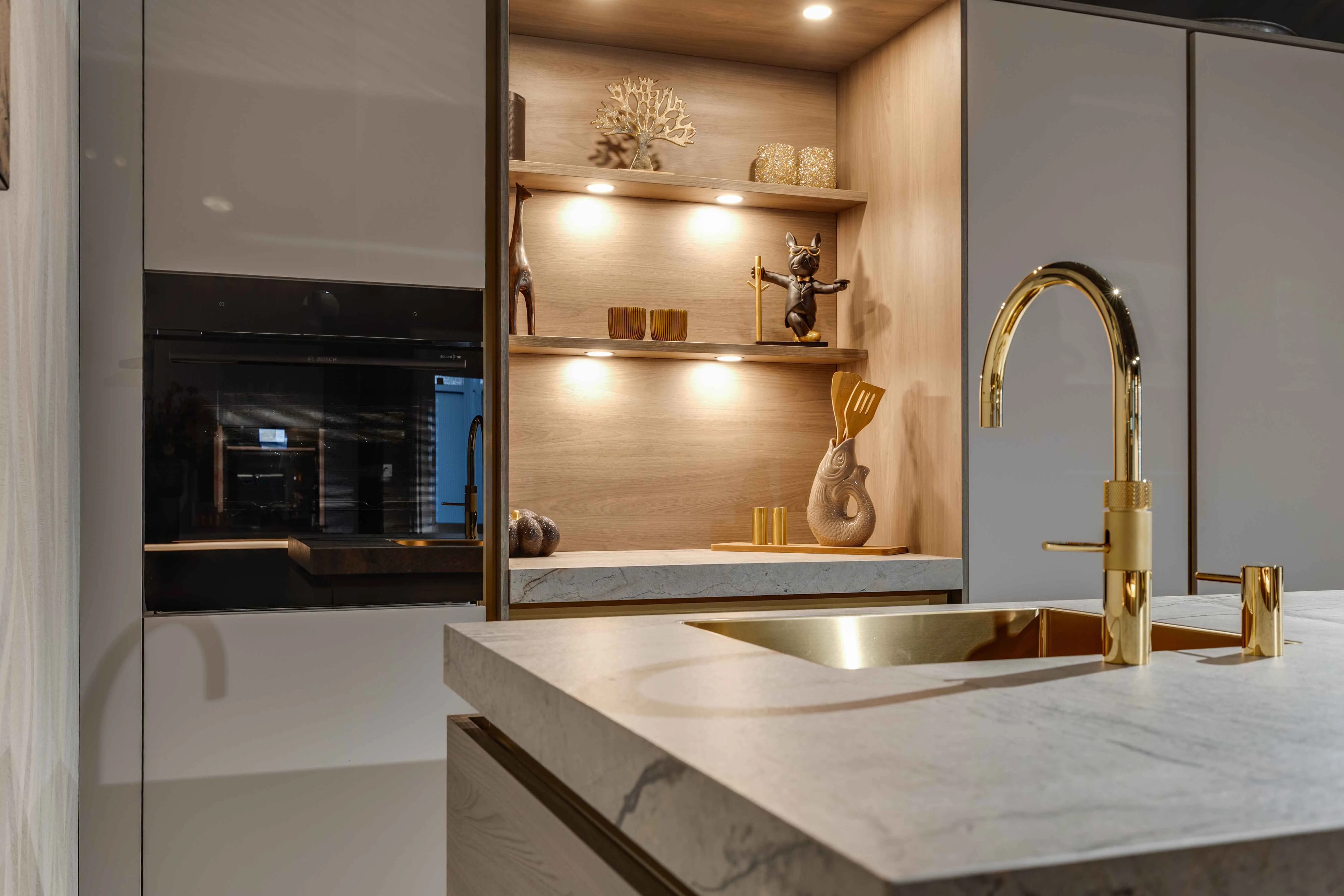 Moderne keuken met gouden kraan, marmerlook werkblad en houten nis - Showroom Goor Marboma