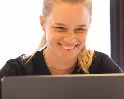 Smiling woman looking at a laptop screen.