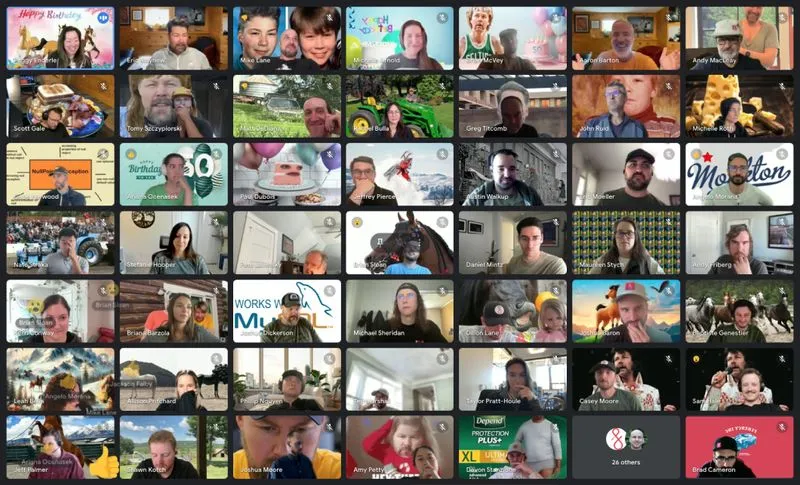 Virtual video call screenshot showing a grid of over 40 diverse participants smiling and celebrating, some with birthday decorations and balloons.