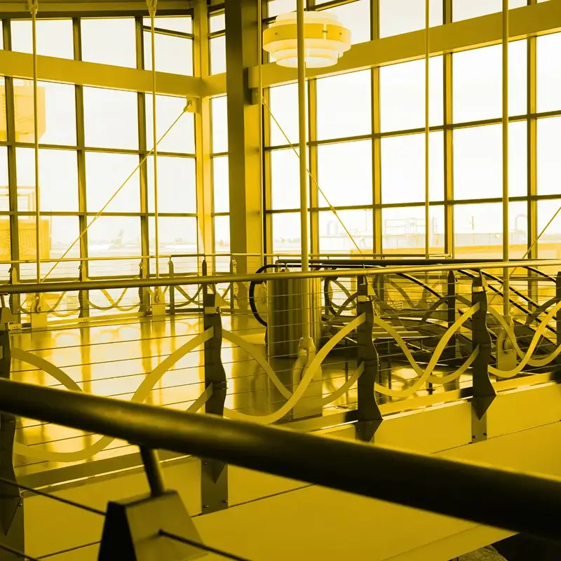 Leerer moderner Flughafen-Terminal mit großen Fensterfronten und Metallgeländern.