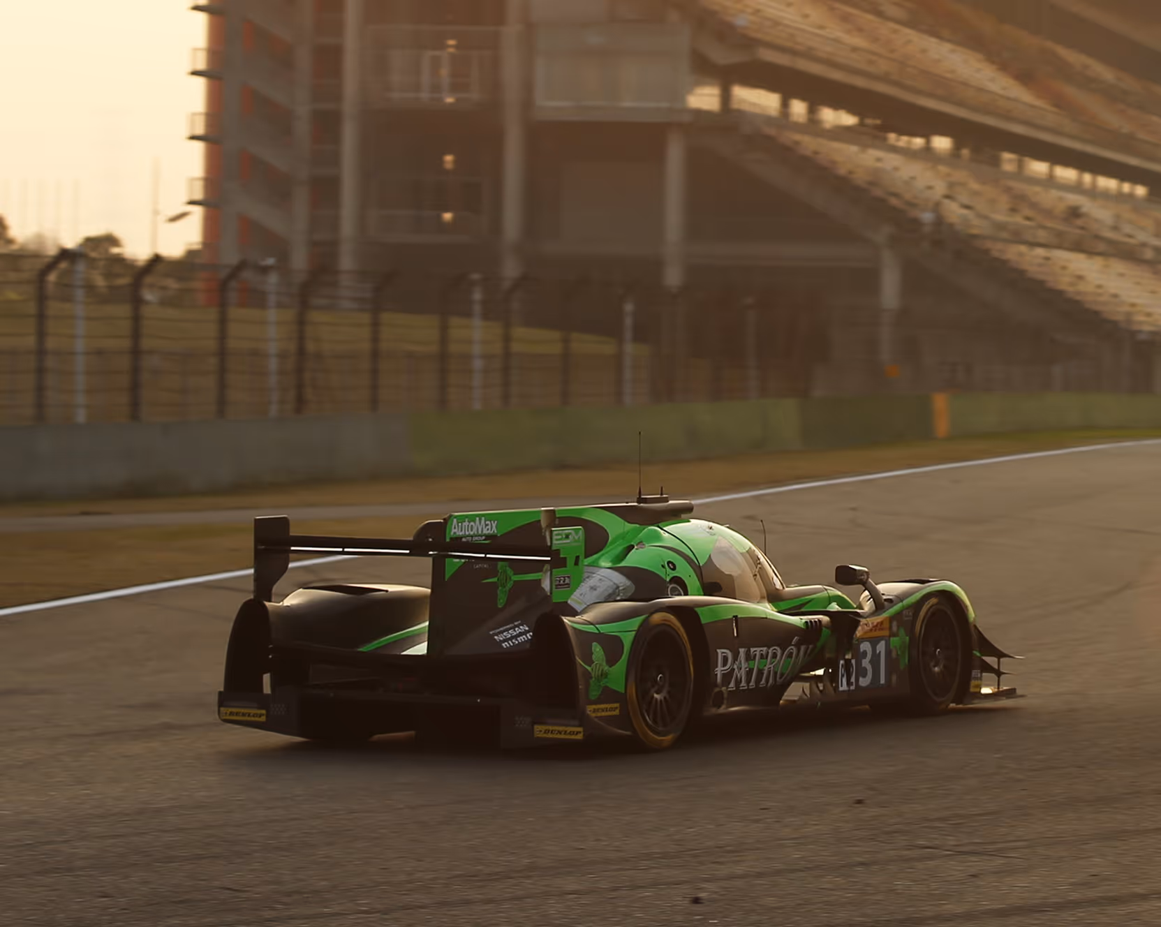 Voiture de course verte sur une piste avec gradins et structure moderne en arrière-plan au coucher du soleil.