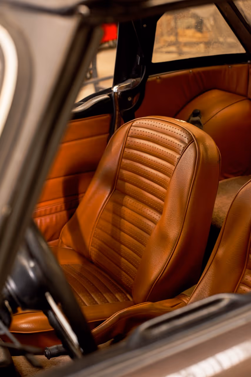 Siège en cuir marron perforé à l'intérieur d'une voiture vintage.