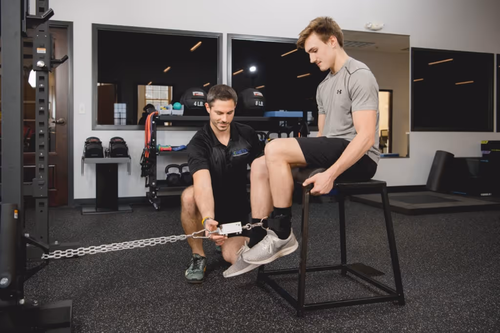 young man testing hamstring strength using a dynamometer with a physical therapist