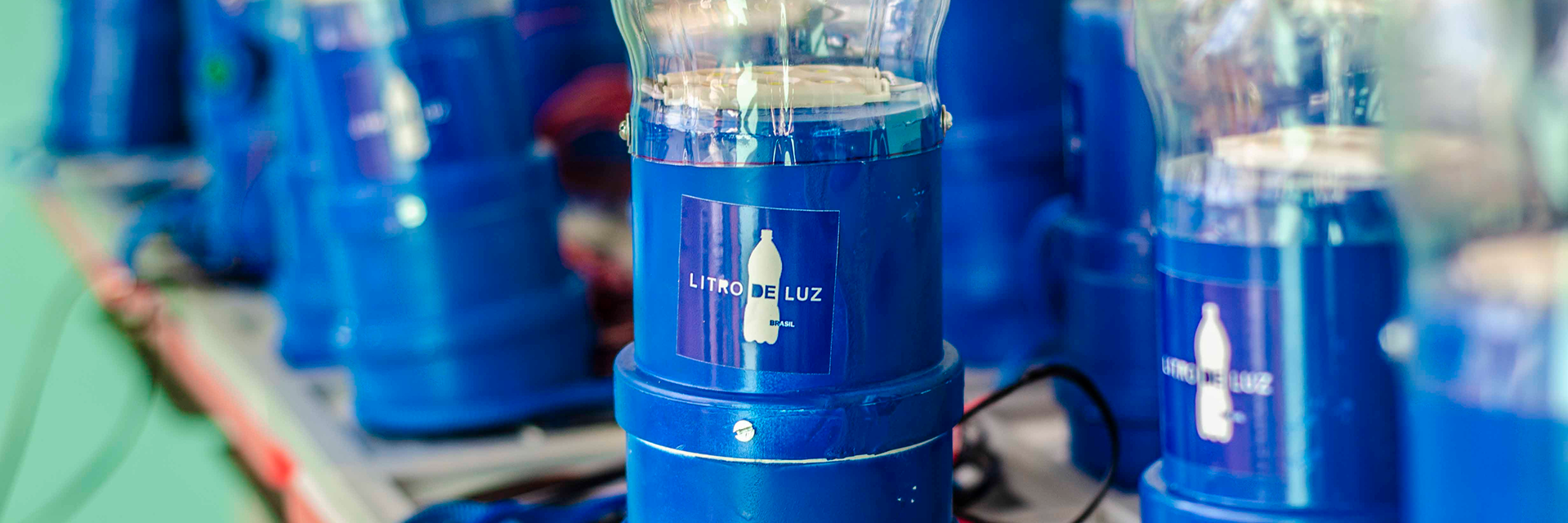 Blue plastic solar bottle lights labeled 'Litro de Luz' arranged in a row.