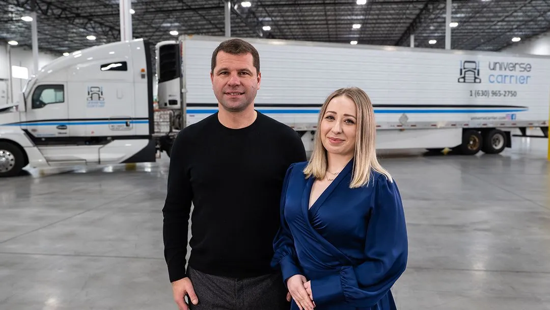 Universe Carrier CEO and Operations Manager laughing standing in front of a truck
