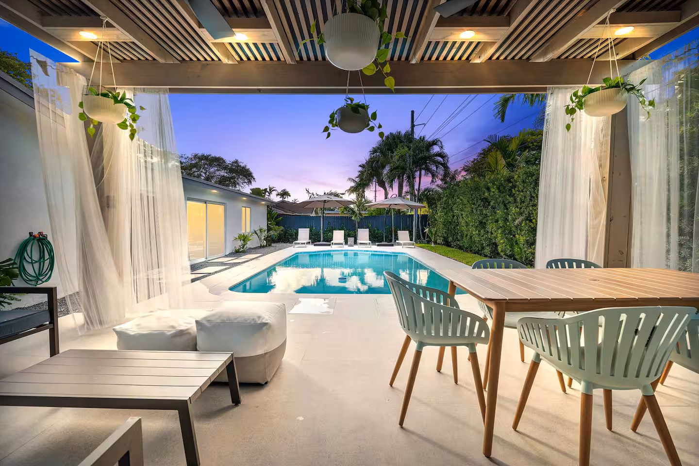 A covered patio and swimming pool area of a modern Miami villa. 