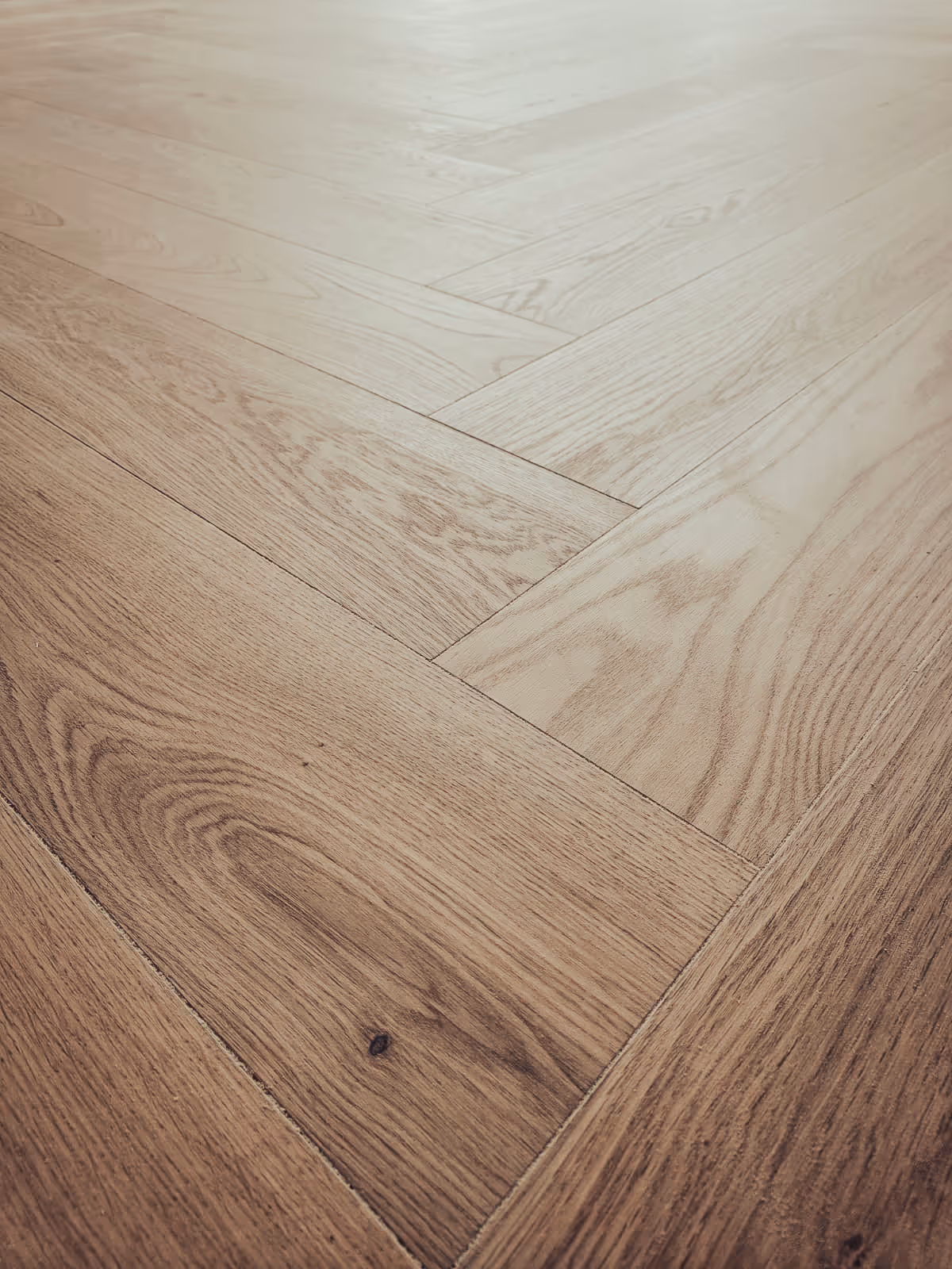 Lähikuva vaaleasta parkettilattiasta, jossa on kalanruotokuvio.