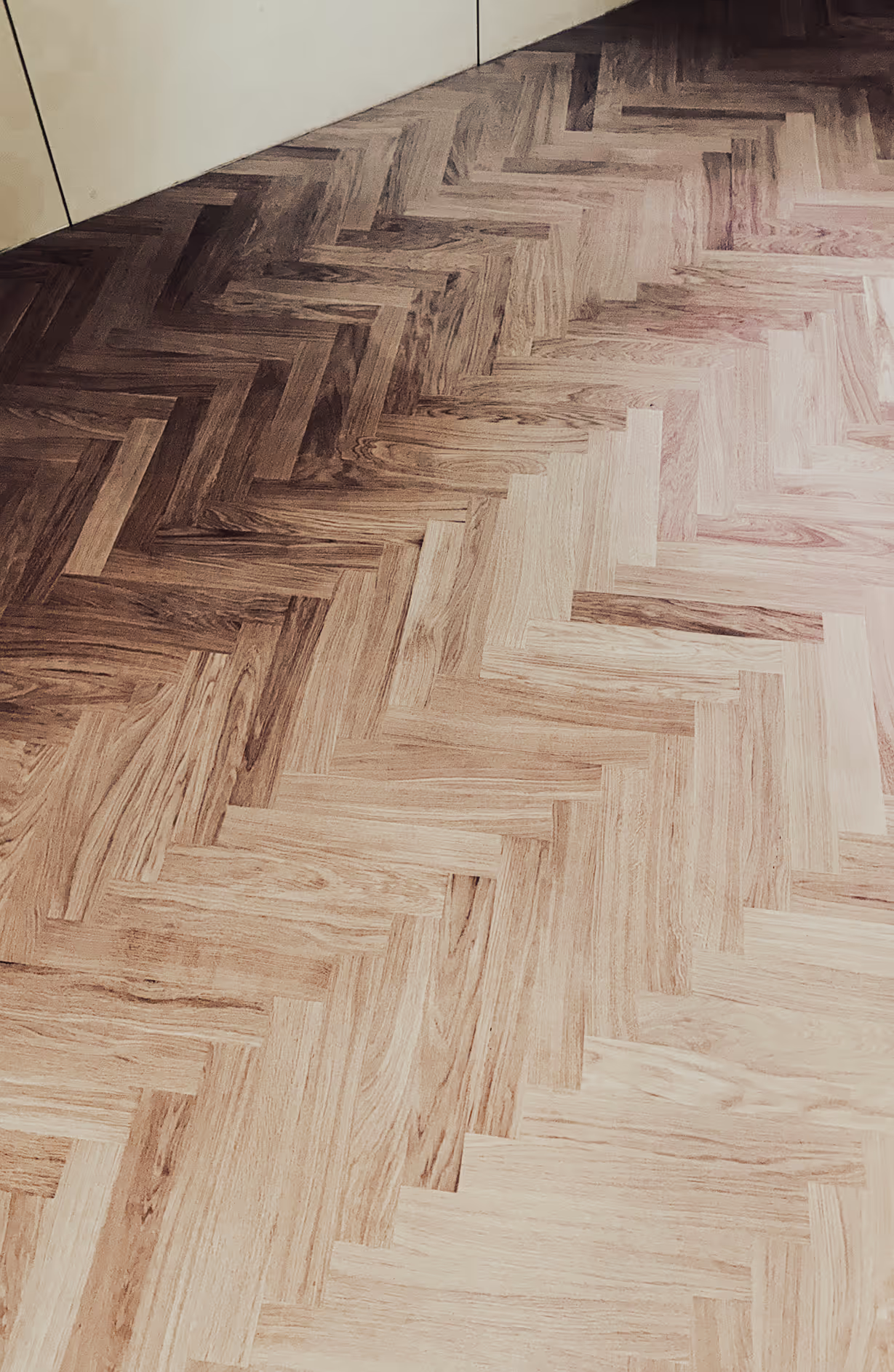 Vaalean ja tumman puunsävyjen kalanruotokuvioinen parkettilattia.