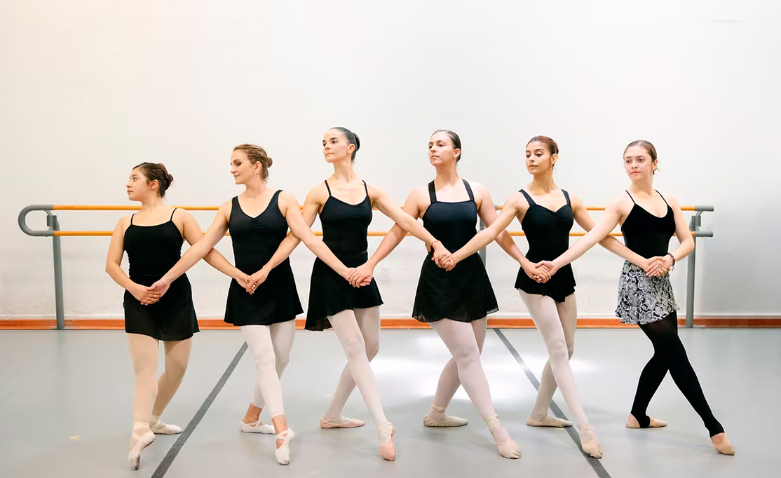 Maestra y alumnas de Danza Clásica practicando movimiento en conjunto.