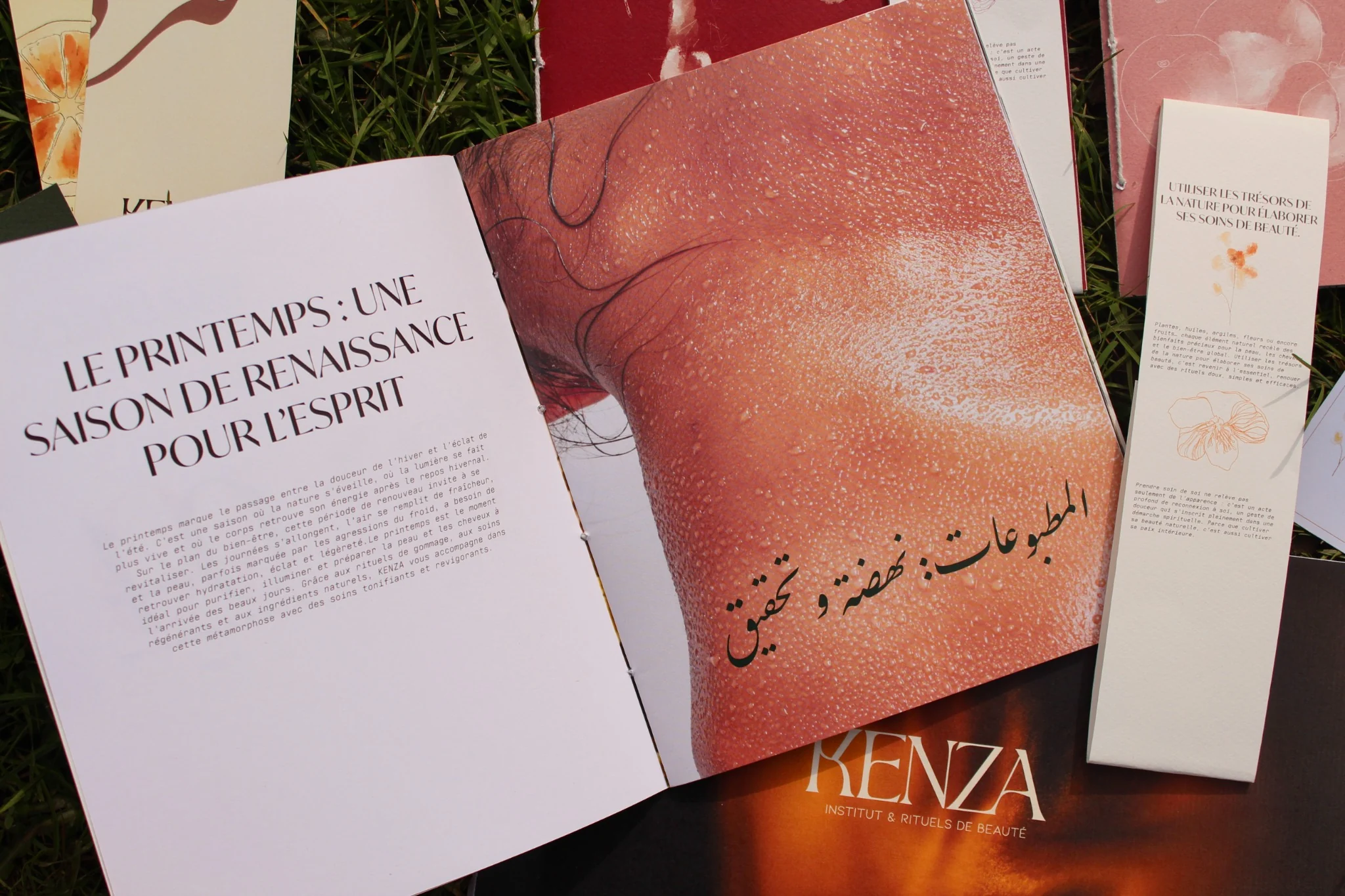 Un livre vert foncé intitulé Printemps avec des illustrations florales, posé sur un fauteuil en velours beige.