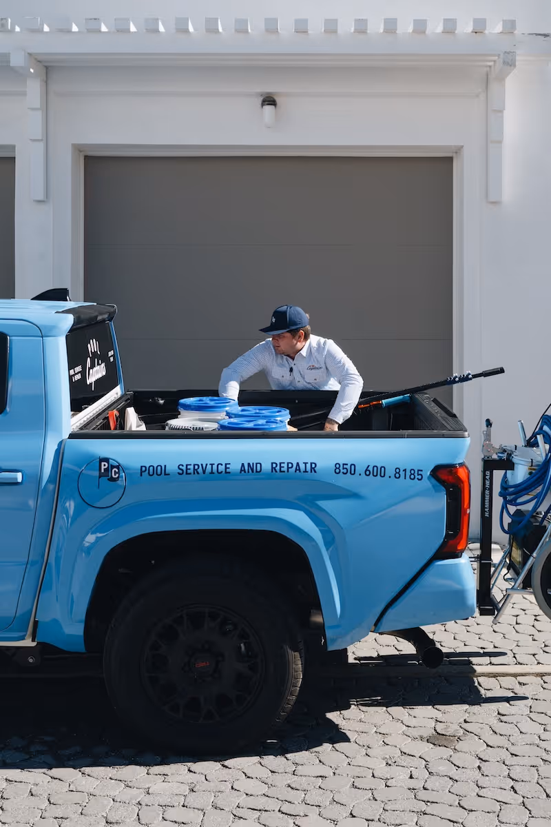 Man in uniform loading equipment into the back of a blue pickup truck