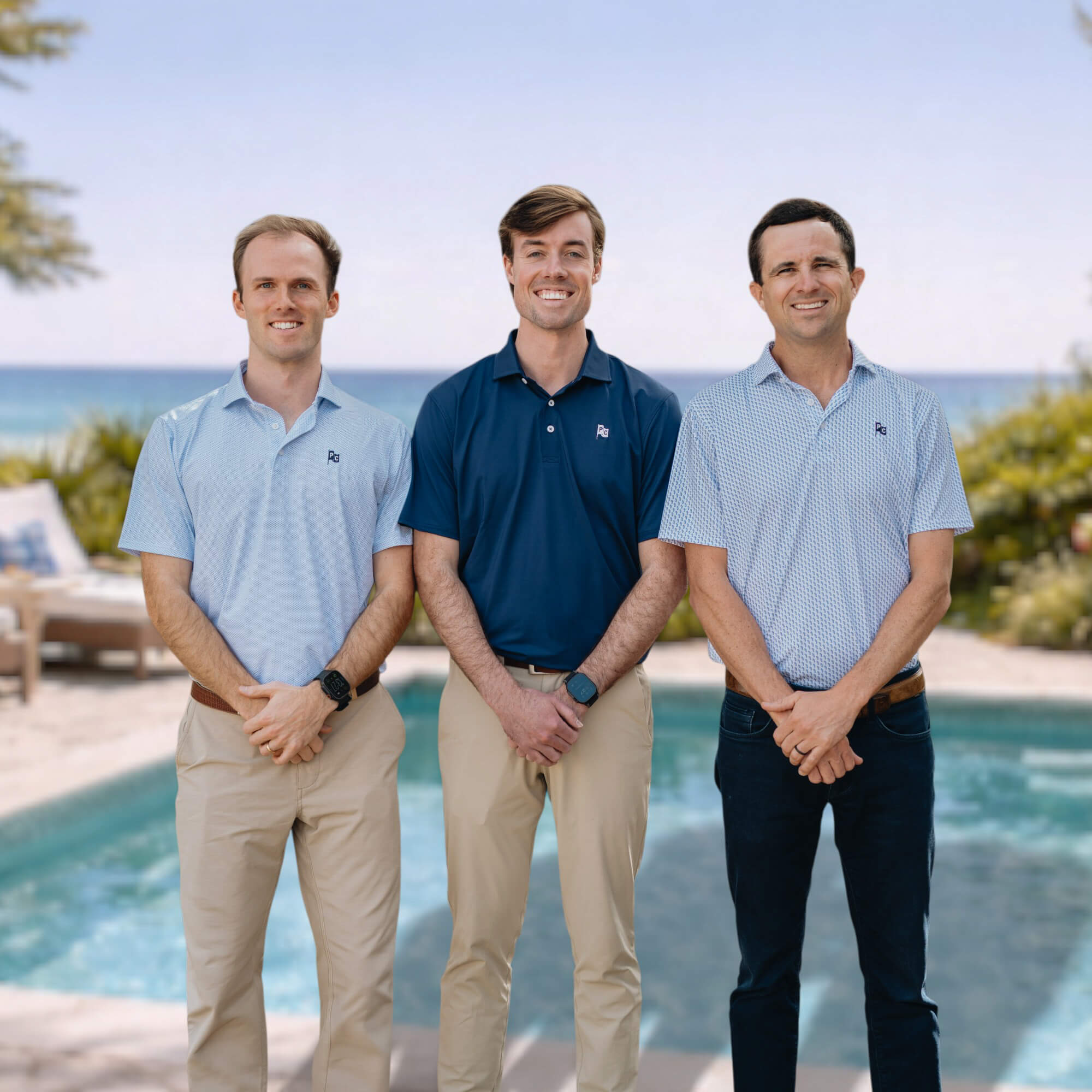 Three founders of Pool Captains standing by a pool with ocean and greenery in the background