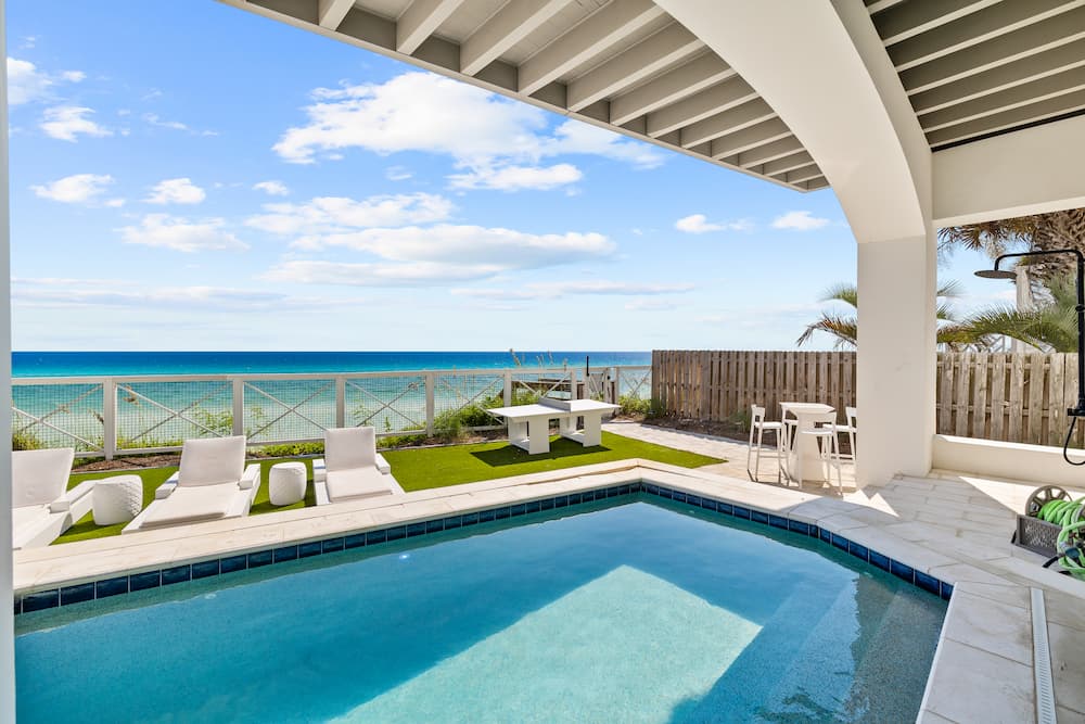 Gulf-front Emerald Coast vacation rental pool with loungers and an ocean view