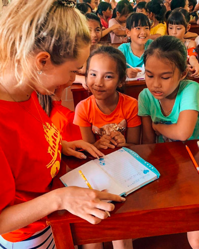 Camp participant works on a classroom workbook with two kids.
