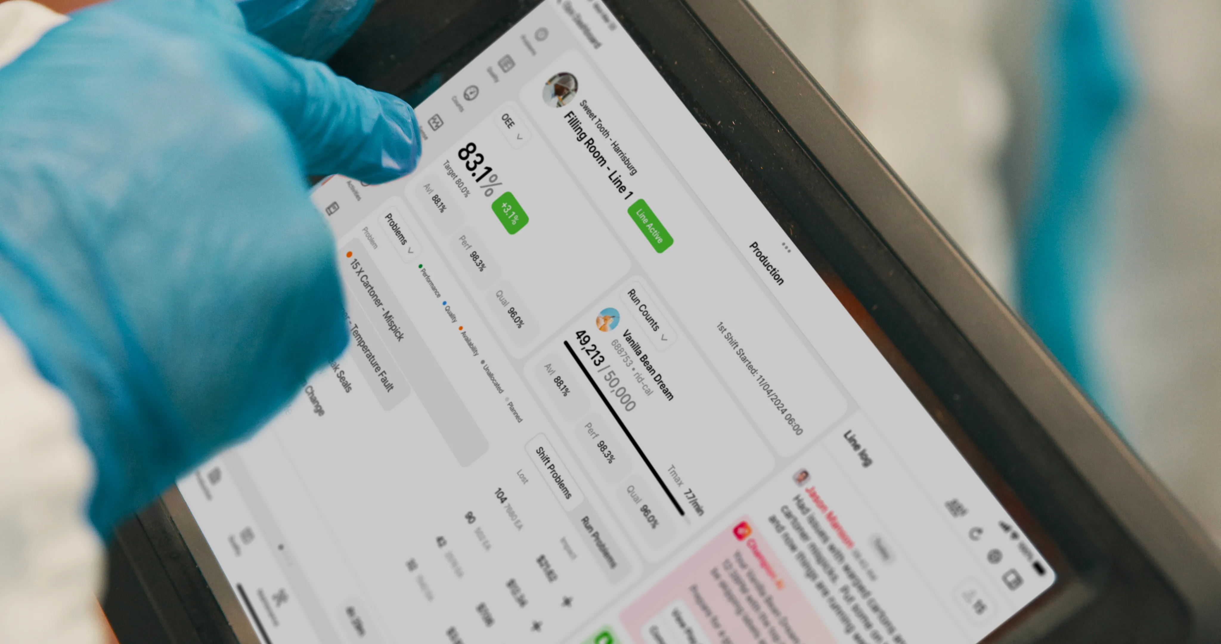 Person wearing blue gloves interacting with a tablet displaying production line metrics and status.