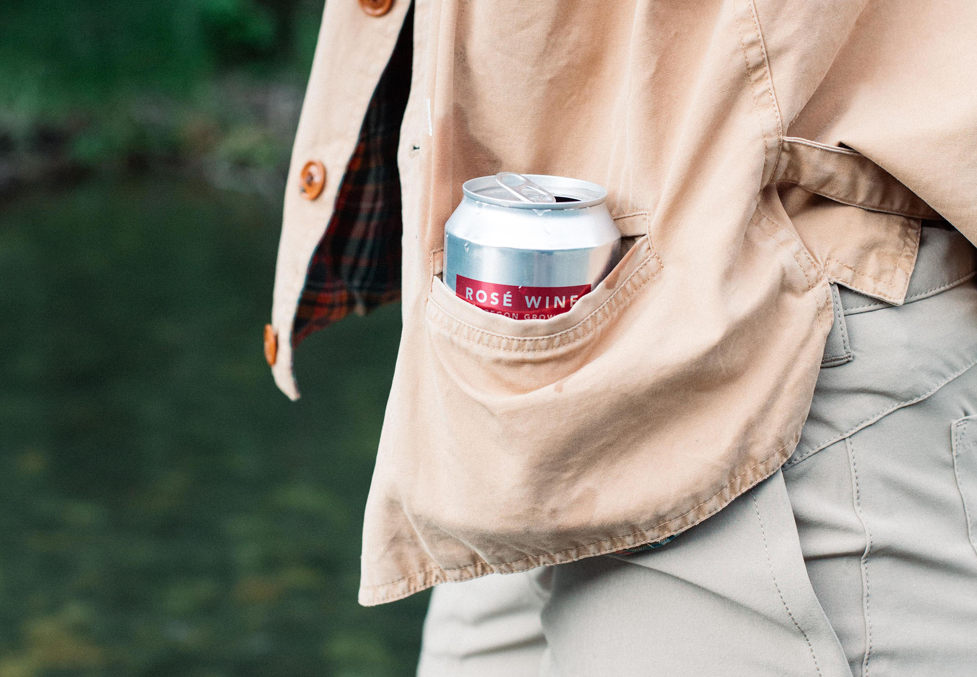 Person wearing beige jacket with a can of rosé wine in the jacket pocket.