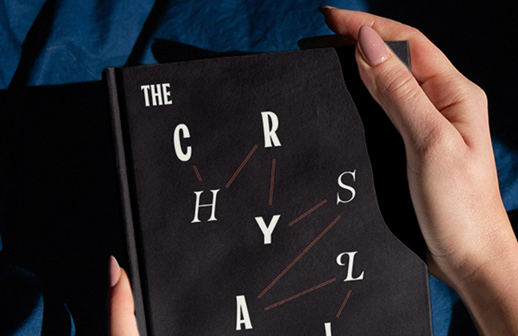 Two hands holding a black book with a title reading "The Chrysalids"
