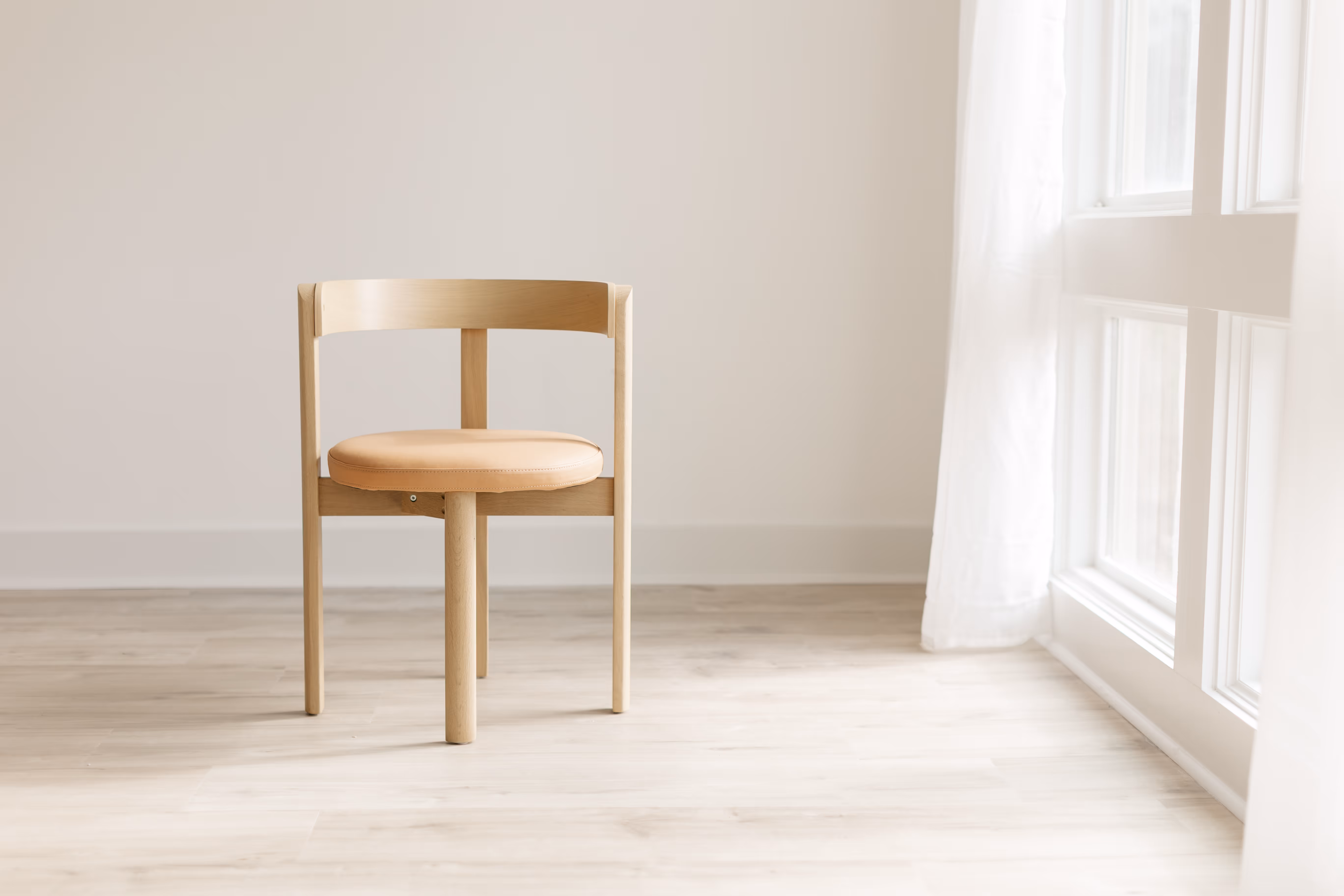 A wooden chair, next to a window at Brightroom Studio, with natural light pouring in from a tall window