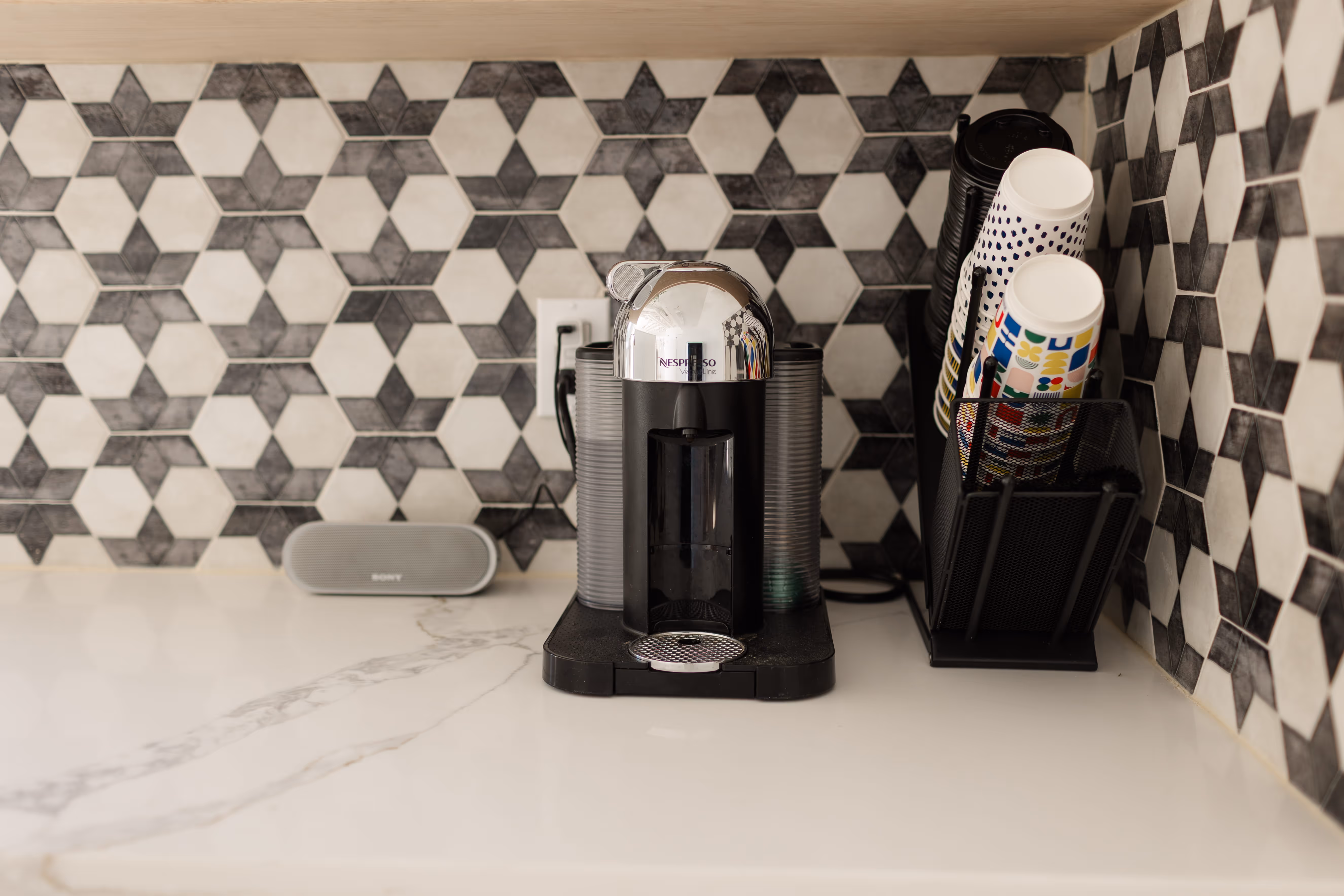 A coffee machine sitting on a coffee bar, next to a bluetooth speaker.