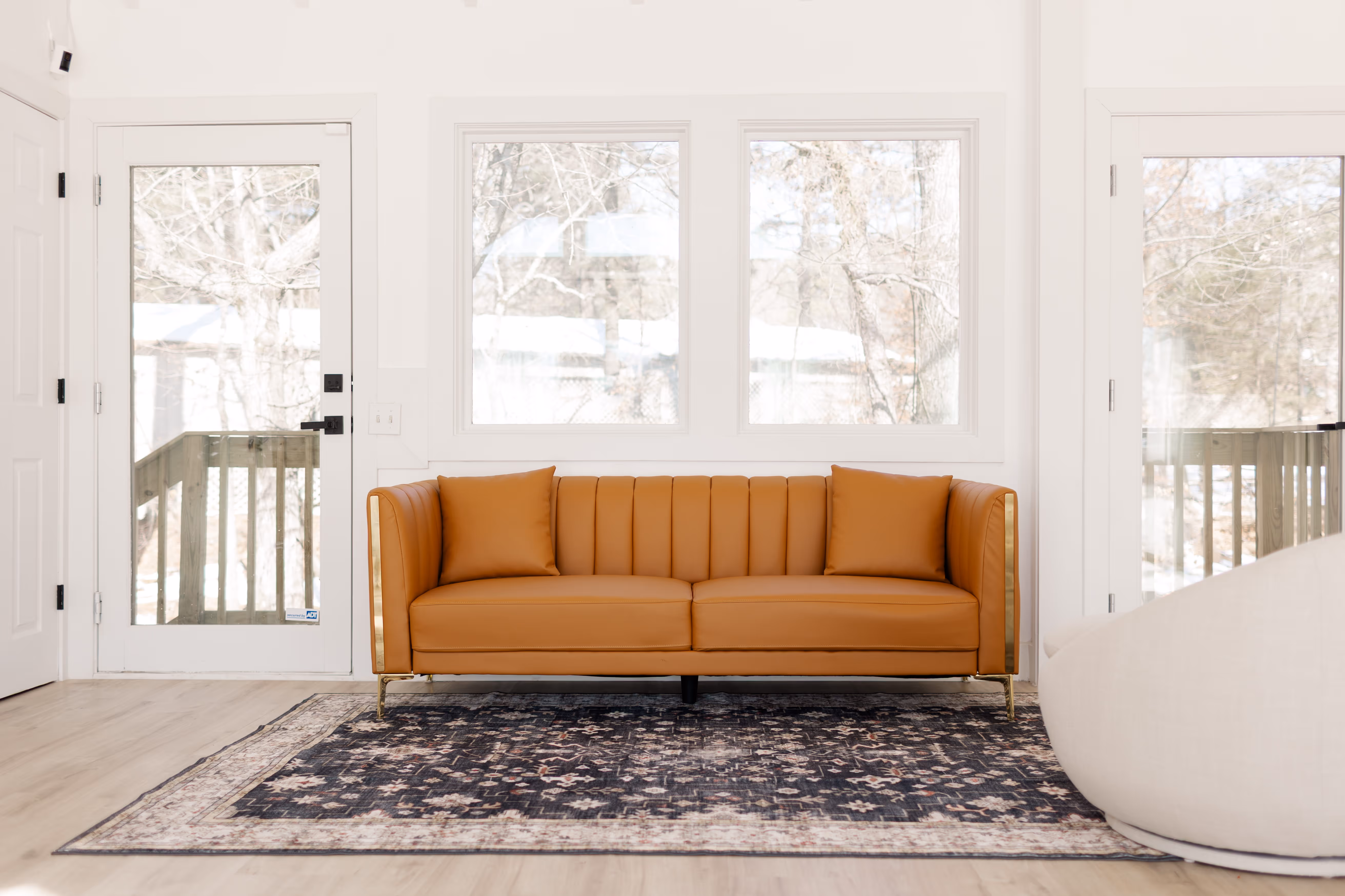 A modern couch sitting in front of a backdoor and several windows in Brightoom Studio