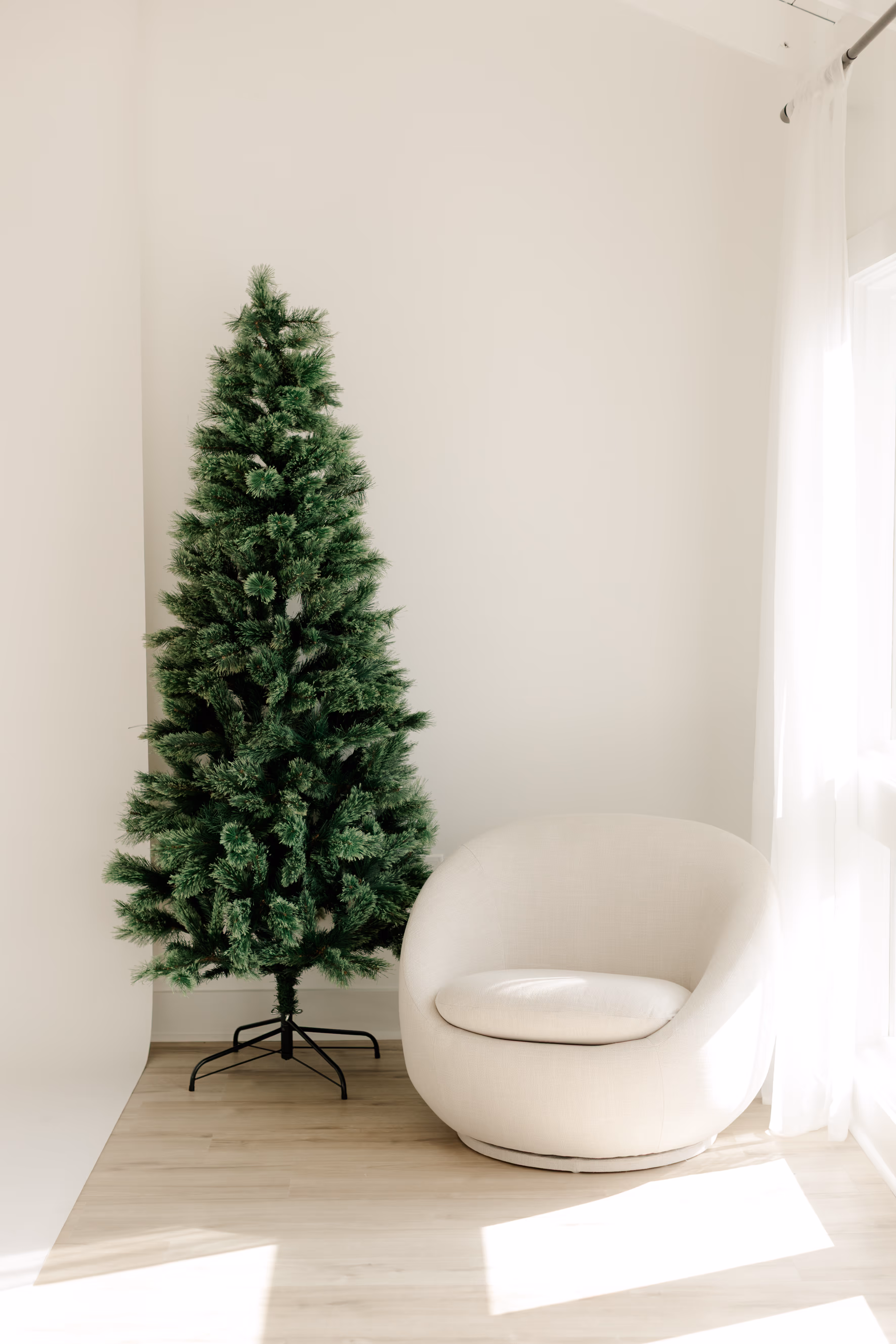 A christmas tree and chair placed next to a window, with natural light beaming into Brightroom Studio