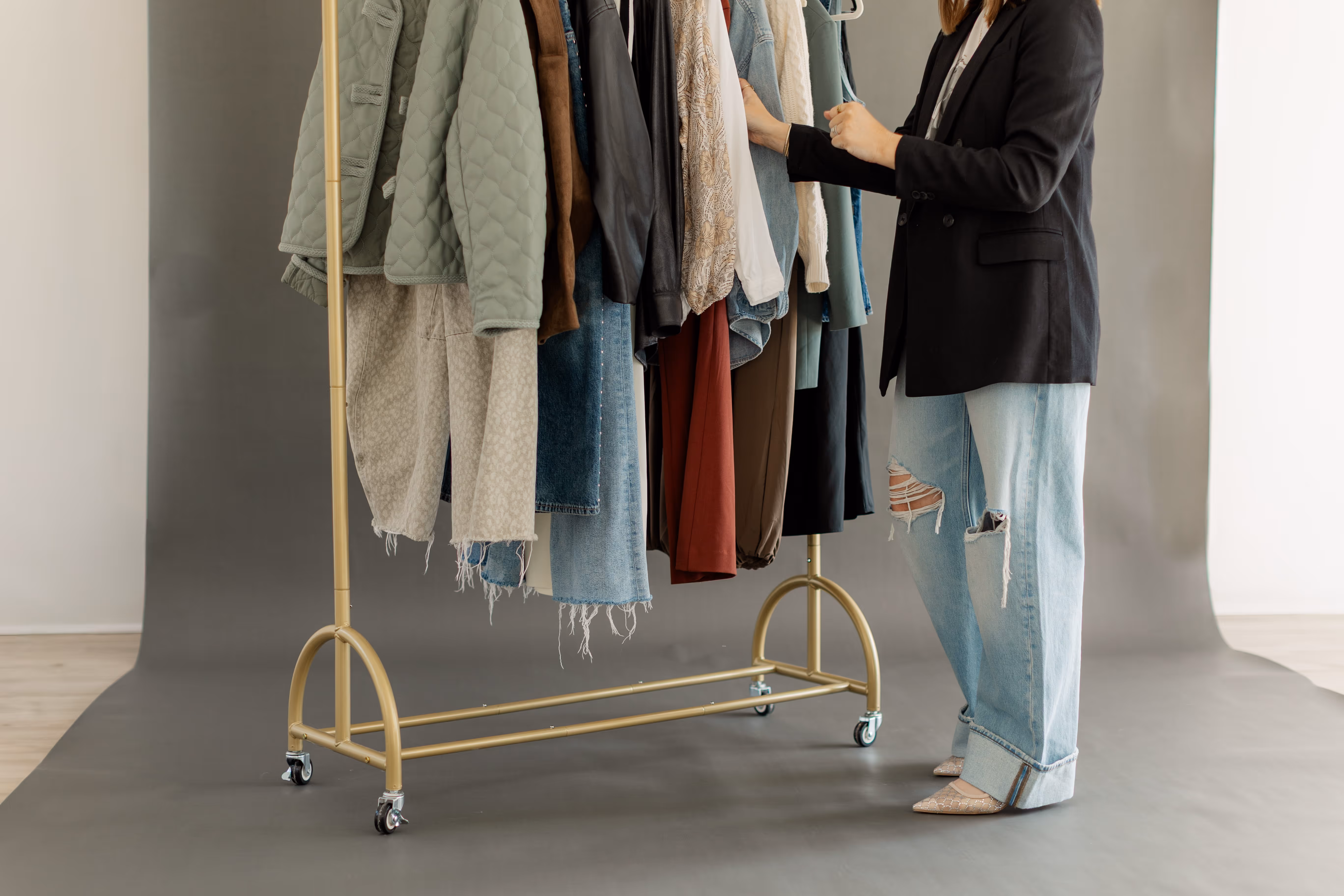 A model standing next to a clothes rack in front of a grey backdrop in Brightroom Studio