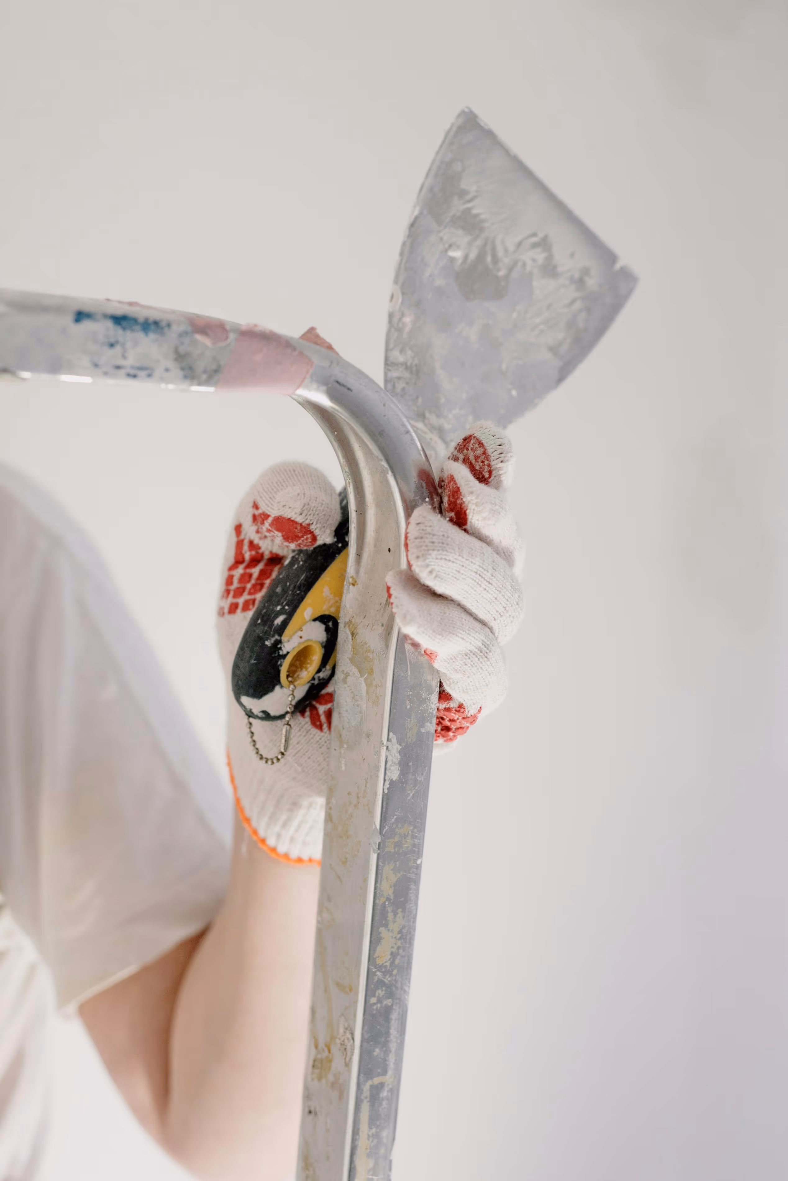 main qui tient une truelle sur un escabeau