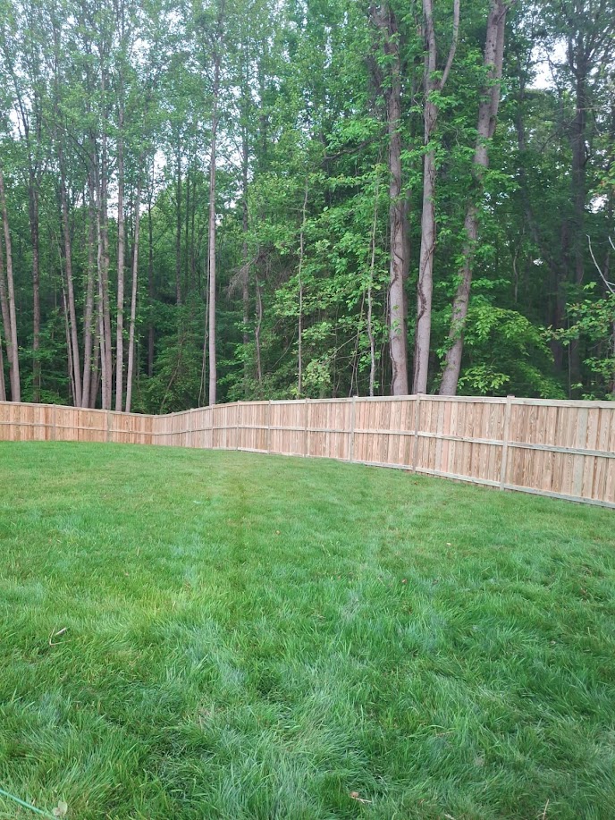 Long wood privacy fence enclosing a backyard lawn at a residential property in Northern Virginia