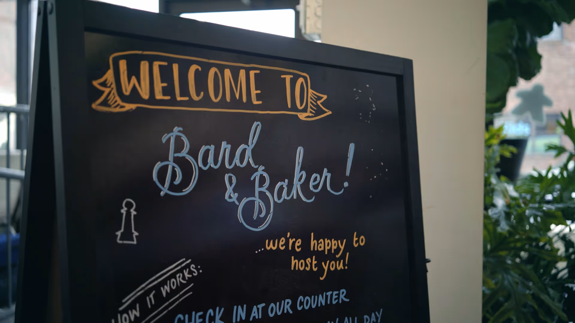 Chalkboard sign reads Welcome to the boardgame cafe with a note about checking in at the counter.
