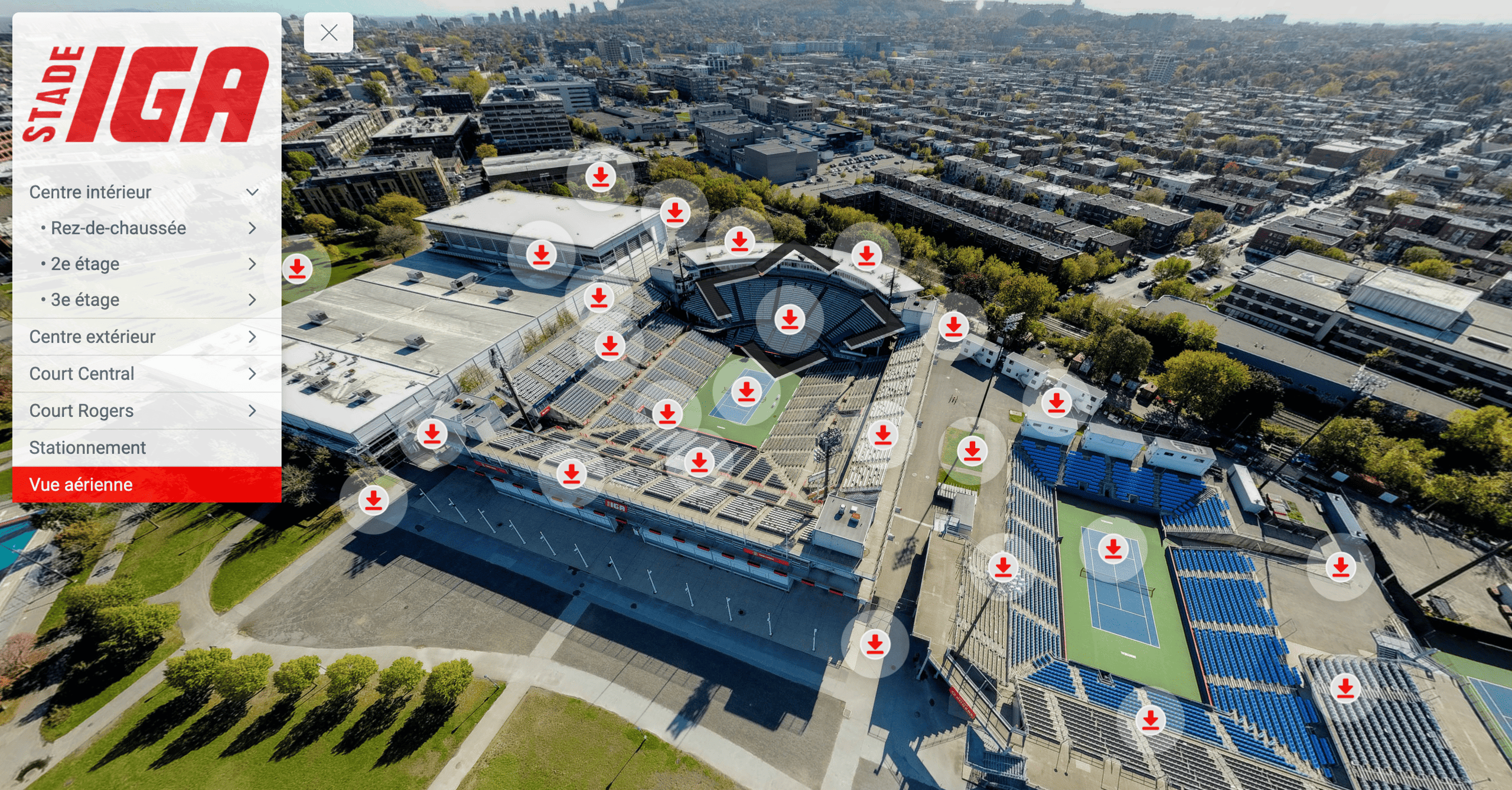 Aerial view of Stade IGA tennis complex with multiple courts and seating areas, surrounded by urban buildings and streets.