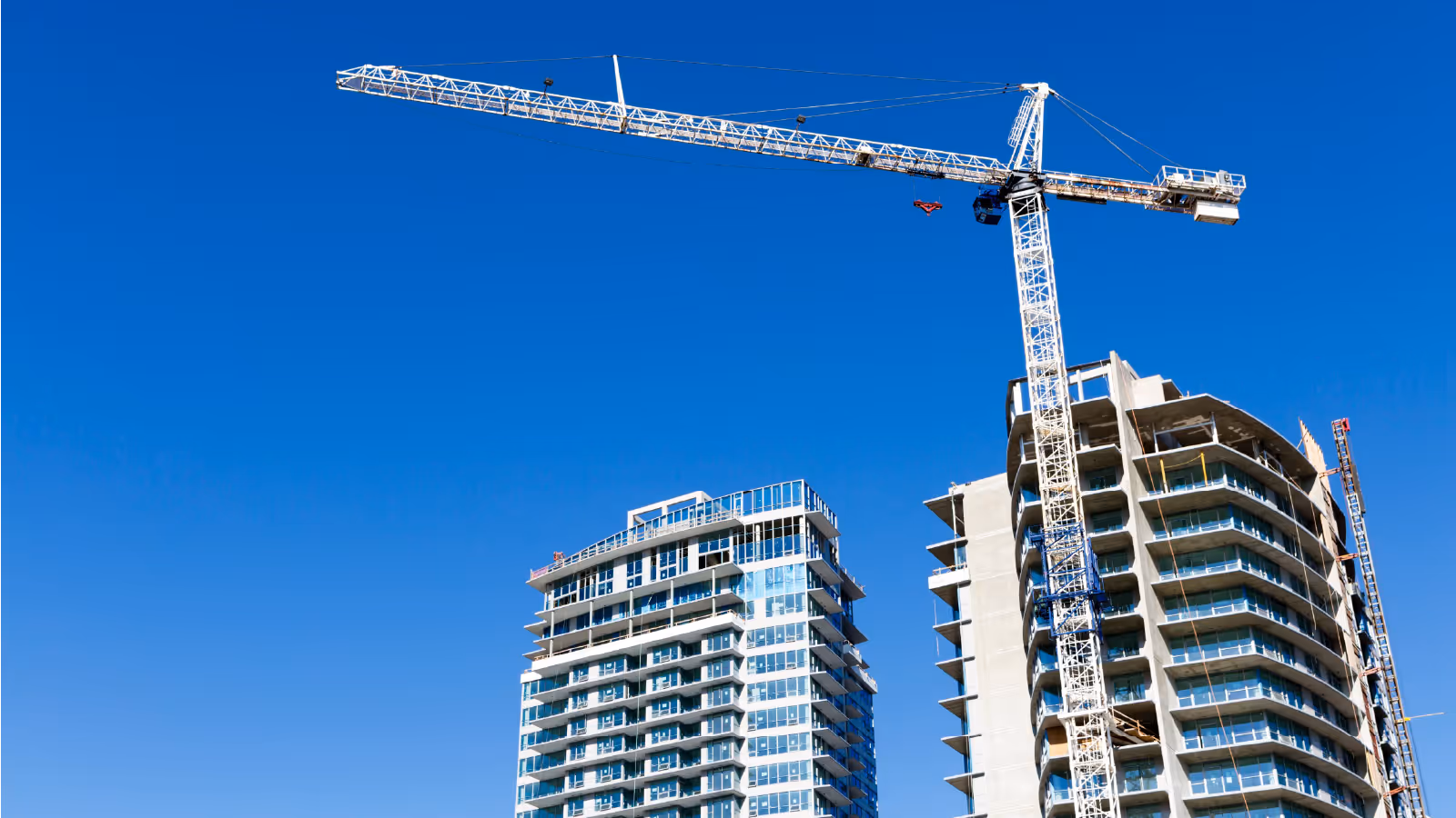Tower crane working beside high rise residential buildings under construction