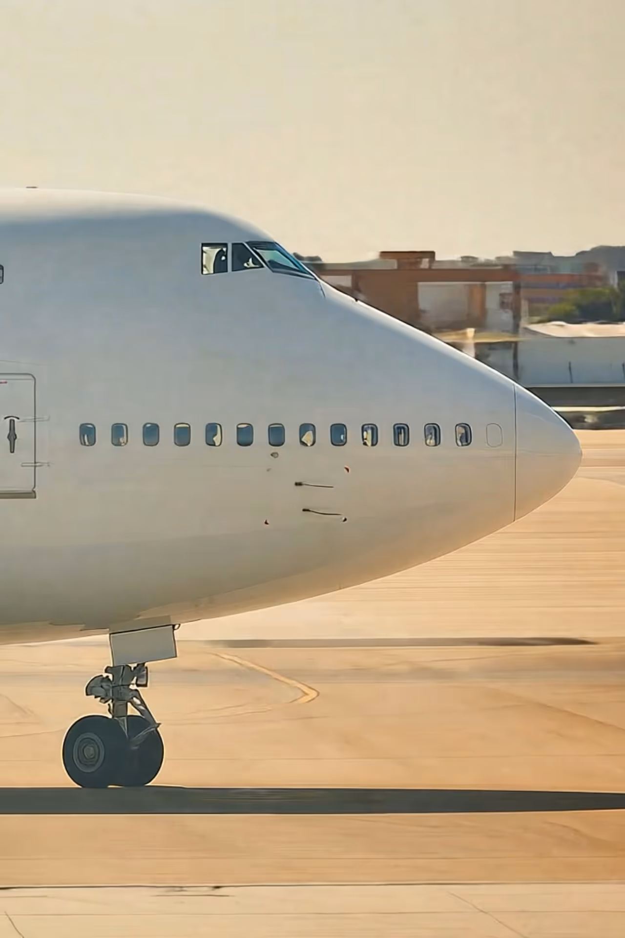 Vue rapprochée de la partie avant d'un avion blanc sur une piste avec le train d'atterrissage avant visible.